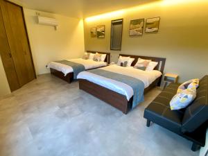 een hotelkamer met 2 bedden en een bank bij Sky Blue Villa沖縄 in Jima
