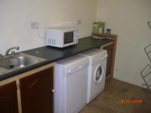 a kitchen with a washing machine and a microwave at Traditional Stone Cottage 300 years+ in Galway