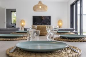 una mesa de comedor con platos y vasos. en Superbe Villa au Calme avec Piscine Chauffée à 5 min de la Plage de Penvins, en Sarzeau