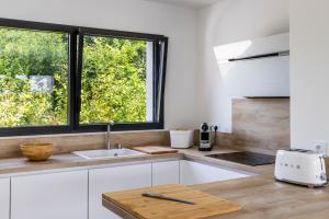 cocina blanca con fregadero y ventana en Superbe Villa au Calme avec Piscine Chauffée à 5 min de la Plage de Penvins, en Sarzeau
