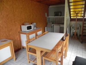 eine Küche mit einem Tisch, Stühlen und einer Mikrowelle in der Unterkunft Camping Le Castella in Luzenac