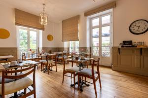 a restaurant with tables and chairs and a clock on the wall at Hôtel & Espace Bien-être La Maison du Lierre in Biarritz