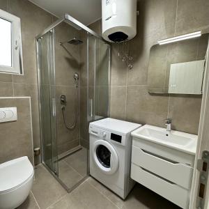 a bathroom with a washing machine and a sink at Akapulco Apartments in Bar