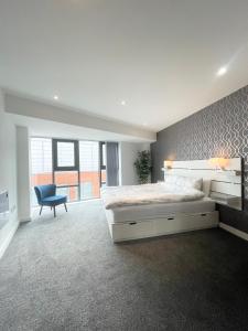 a bedroom with a large bed and a blue chair at The Works-Fresh 2bed in centre, opposite Arndale. in Manchester