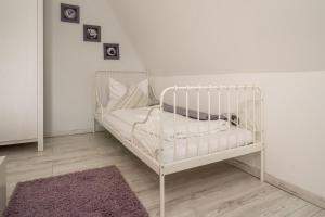 a white crib in a room with a purple rug at FeWo 1 ''Am Rodelberg'' in Priborn