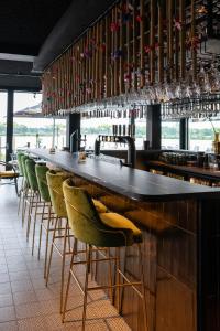 een bar met een rij groene stoelen en wijnglazen bij Boutique Hotel de Bungelaer in Beers