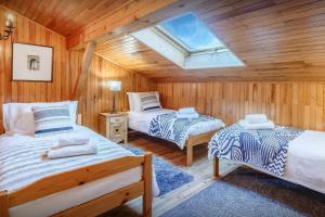 two beds in a wooden room with a skylight at Chalet Bellanis - OVO Network in Morzine