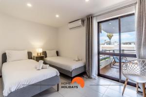 two beds in a room with a balcony at #169 T3 Medronheira by Home Holidays in Olhos de Água +53 photos