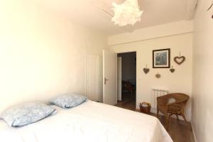 a bedroom with a white bed and a chandelier at Joli appartement avec balcon au coeur de Forcalquier in Forcalquier