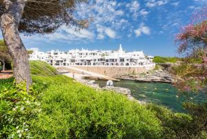 a large white building on a hill next to a river at Villa Palmera in Cala'n Porter