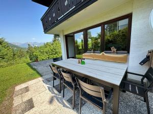 einen Holztisch und Stühle auf der Rückseite eines Hauses in der Unterkunft FeWo Zeitlos in Berchtesgaden