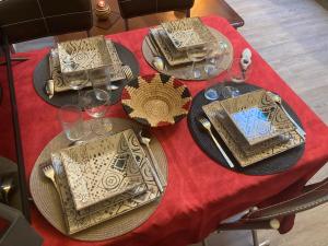 a table with two plates and glasses on a red table cloth at LES ROCHES gîte in Corme-Royal