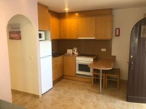 a small kitchen with wooden cabinets and a white refrigerator at Relax Playa Son Bou, Menorca in Son Bou