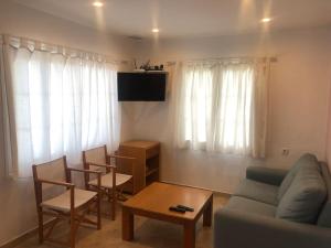 uma sala de estar com um sofá, cadeiras e uma mesa em Playa Son Bou, Menorca em Son Bou