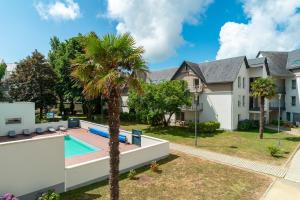 een huis met een zwembad en een palmboom bij Le Kichen - Appt proche de la plage in Bénodet