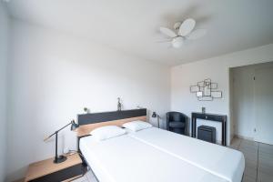 a white bedroom with a bed and a ceiling fan at La Casa de Cricri - Appartement climatisé in Perpignan