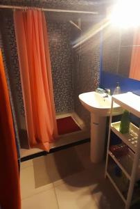 a bathroom with an orange shower curtain and a sink at Zen Studio in Rabat