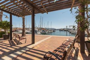 patio z dwoma ławkami i łodziami w przystani w obiekcie Vacaciones Sol y Playa w mieście Puerto de Mazarrón