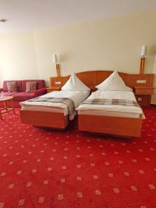 two beds in a room with a red carpet at Landhotel Westerwaldgrill in Höhn