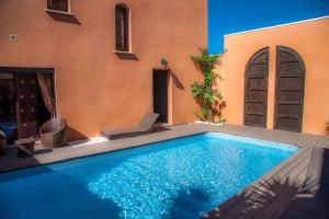 a swimming pool with a chair next to a house at Chambre Meknes, Riad 7 au village naturiste Couple only in Cap d'Agde