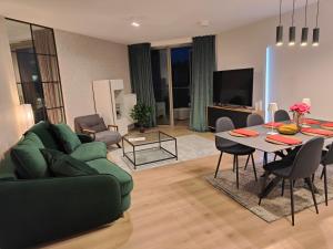 ein Wohnzimmer mit einem grünen Sofa und einem Tisch in der Unterkunft Pinea Apartments in Pobierowo