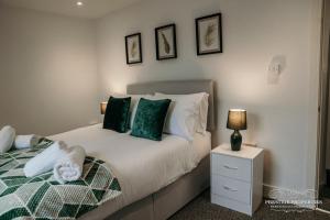 um quarto com uma cama com almofadas verdes e brancas em Fell Croft by Prestige Properties SA em Dalton in Furness