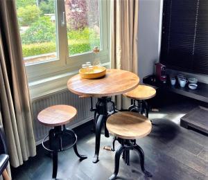 a wooden table with four stools in front of a window at Studio het Strandhuis KA05 in Vlissingen