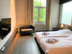 a hotel room with two beds and a chair at Studio het Strandhuis KA05 in Vlissingen