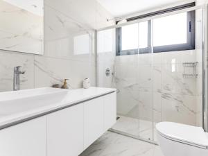 a white bathroom with a sink and a toilet at Sanders Park Central Residences in Limassol