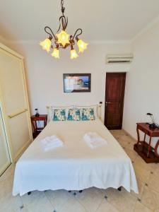 una camera con letto bianco e lampadario pendente di Varigotti Tropical Garden - full floor apartment a Varigotti