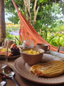 een tafel met een bord eten en een kom eten bij Pousada Quintal dos Sonhos Xandó Caraiva in Caraíva