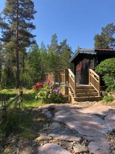 una cabaña en el bosque con una pasarela al porche en Timber cottages with jacuzzi and sauna near lake Vänern en Karlstad