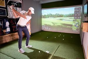 a man is playing golf in a room with a screen at Hotel Crozzon in Madonna di Campiglio