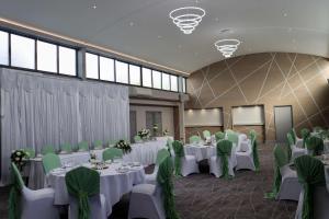 um salão de banquetes com mesas brancas e cadeiras verdes em Best Western Premier Heronston Hotel & Spa em Bridgend