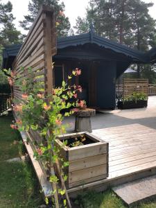 una terraza de madera con una caja de madera con flores. en Timber cottages with jacuzzi and sauna near lake Vänern en Karlstad