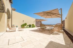 Un patio con sillas, una mesa y una sombrilla. en Villa Chiara, en Lipari