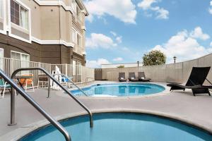 a swimming pool with chairs and a building at La Quinta by Wyndham Hesperia Victorville in Hesperia