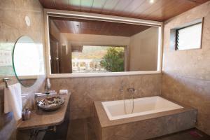 uma casa de banho com uma banheira, um lavatório e um espelho. em Urmilaa Green County Resort 35 KM From Kolhapur em Kolhapur