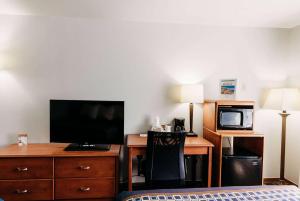 Travelodge by Wyndham Worland في Worland: غرفة فندقية بسرير ومكتب مع تلفزيون