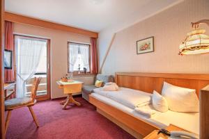 a bedroom with a bed and a chair and a window at Berg- und Aktivhotel Edelsberg GmbH in Bad Hindelang