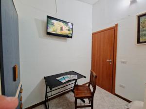 Habitación con mesa y TV en la pared. en Luna & Sole, en Santa Maria la Palma