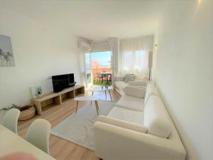 een witte woonkamer met een witte bank en een tv bij Apartamento Con Piscina y Gran Terraza con Vistas - Muy cerca de la playa, el centro y la estación in Vilassar de Mar