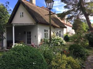 een klein wit huis met een rieten dak bij Zauberhaftes englisches Cottage am Gutshaus in Groß Schoritz