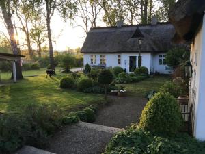 een klein wit huis met een tuin met een tuin bij Zauberhaftes englisches Cottage am Gutshaus in Groß Schoritz