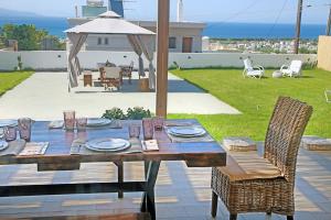 a wooden table with plates and glasses on it at Pilot's Cottage Villa With Sea View in Tavronitis