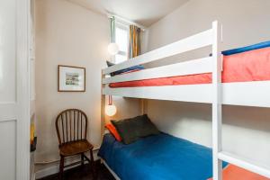a bedroom with a bunk bed and a chair at Cliff-top Coastguard's Cottage, an Off-Grid Escape in Weybourne
