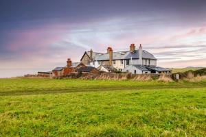 a large house on top of a grass field at Cliff-top Coastguard's Cottage, an Off-Grid Escape in Weybourne