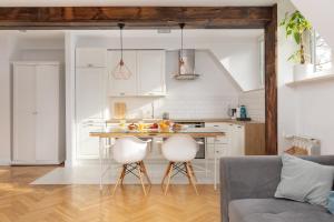 a kitchen with a table and two white chairs at ECRU Warsaw Apartment near Vistula River WWA1 in Warsaw