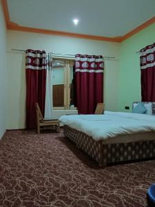 a bedroom with two beds and red curtains at Maryoul Guest House, Hunder Nubra in Hundar