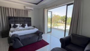 a bedroom with a bed and a chair and a large window at Lifestyle Lodge Hotel in Vereeniging
